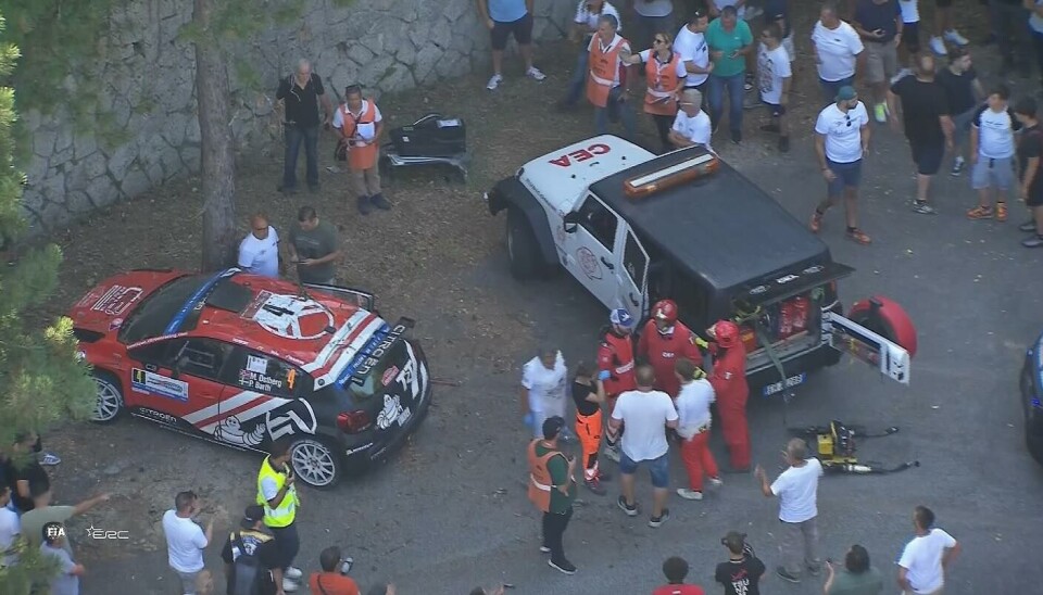 TV-bildene viser øyeblikkene kort tid etter avkjøringen rett i et tre. Her ser vi kartleser Patrik Barth (blå caps og rød dress) kommet seg opp på bena igjen etter å ha vært bevisstløs en kort periode etter sammenstøtet.