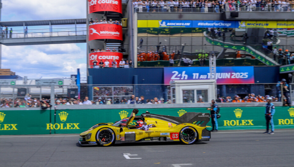 Robert Kubica mottar flagget etter seieren på Le Mans, og venter på å feire med teamkameratene.